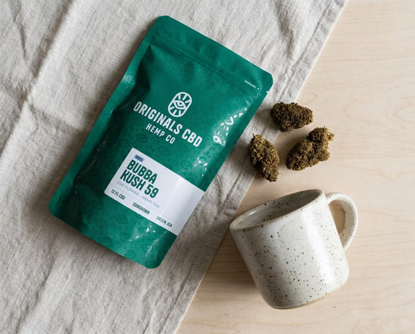 branded packaging with cbd flower next to a mug, all with natural background colours.