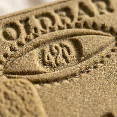 close up image of some hash with the writing 'goldbar 420' sand coloured.