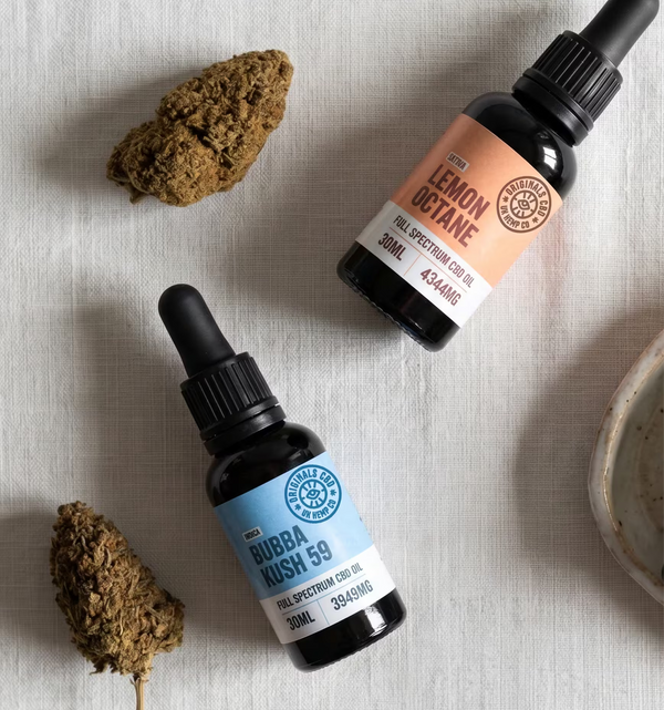 cbd oil and cbd flower on a cream coloured cloth.
